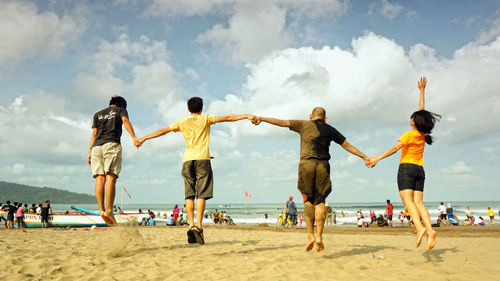 Full length of siblings playing soccer at beach