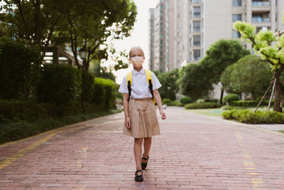 Portrait of young woman walking on footpath