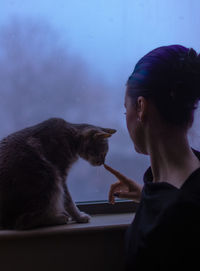 Woman with cat on window at home