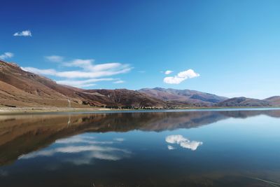 Scenic view of lake and mountains against blue sky