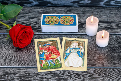 High angle view of tarot cards with candles and rose on table