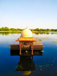 Cross on lake against clear blue sky