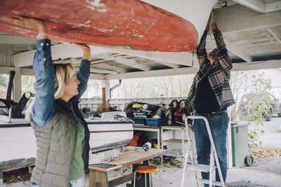 Mature man tying nautical vessel while female friend helping him in garage