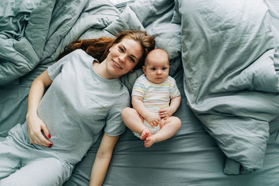 Top view of a caring mommy with a baby on the bed in the bedroom.