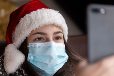 Close-up of young woman wearing mask taking selfie at home