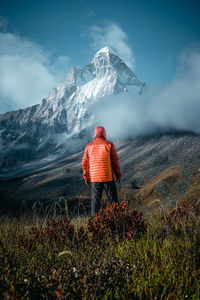 Rear view of person on snowcapped mountain against sky