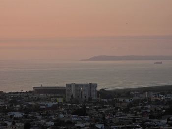 High angle view of buildings by sea against sky at sunset