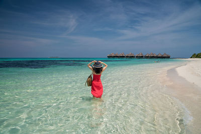 Woman standing on beach against sky