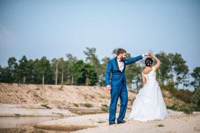 Full length of couple standing against sky