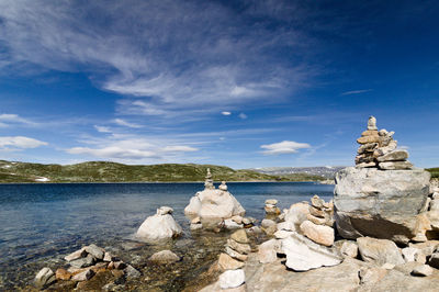 Rocks by sea against blue sky