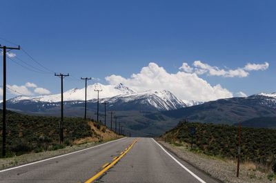 Road by mountains against sky