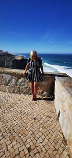 Full length of senior woman standing against sea