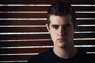 Close-up portrait of handsome young man against wooden wall