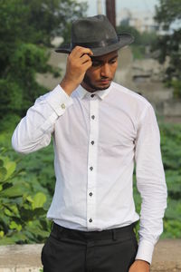 Young man looking away while standing outdoors