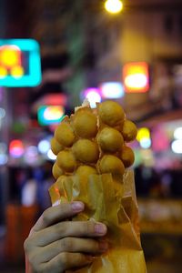 Close-up of hand holding ice cream at night