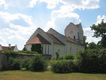 Houses by trees and buildings against sky