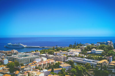 High angle view of buildings and sea against blue sky