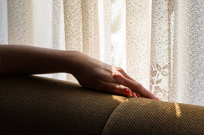 Low section of woman sitting on sofa at home