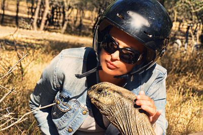 Woman wearing helmet with turtle on field during sunny day