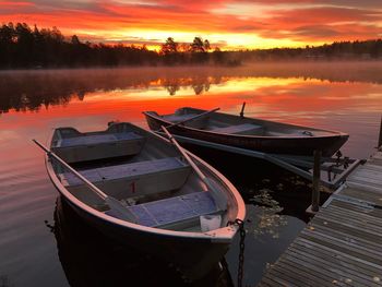 Boat moored in lake against sky during sunset