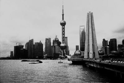 View of skyscrapers by river against sky