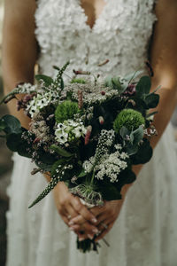 Midsection of woman holding bouquet of flowering plant