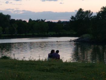 Rear view of people sitting on lakeshore