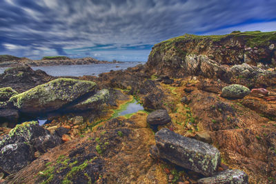 Rocks by sea against sky