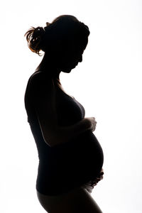 Side view of silhouette of pregnant woman against white background