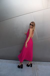 Portrait of young woman standing against wall