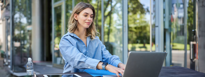 Young woman using laptop while sitting on table