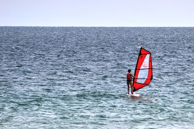 Rear view of woman windsurfing against clear sky