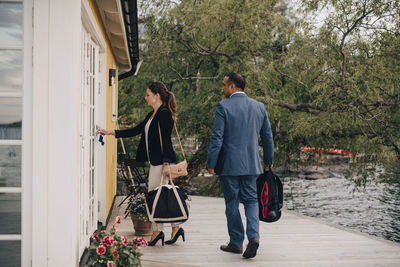 Full length of mature couple unlocking door at holiday villa by lake