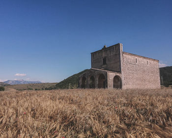 Built structure on field against clear blue sky