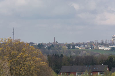 Trees and houses against sky during autumn