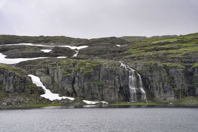 Scenic view of sea and waterfall against sky