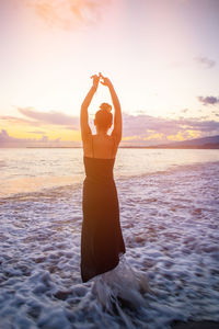 Rear view of woman at beach during sunset