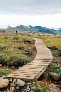 Footpath leading towards mountains against sky