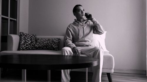 Black and white man hold smart phone while working in the living room of the house 