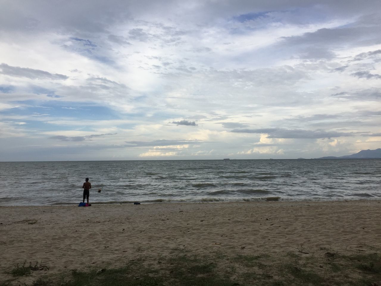 WOMAN STANDING ON BEACH AGAINST SKY