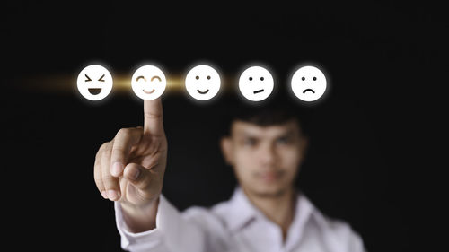 Portrait of man standing against black background