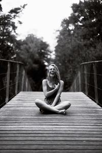 Young woman sitting on footbridge