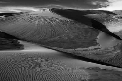 Sand dunes at beach against sky