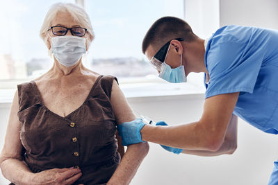 Doctor wearing mask vaccinating patient