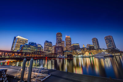 Illuminated cityscape against clear blue sky at night