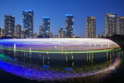 Multi colored light trails on illuminated buildings in city at night
