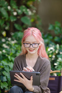 Young woman using mobile phone while sitting on field