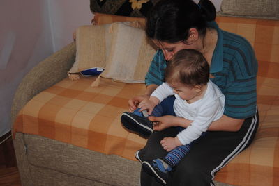 Rear view of boy sitting on laptop at home