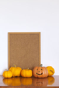 Jack o lantern with pumpkins and bulletin board against white wall