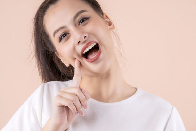 Portrait of beautiful young woman against wall